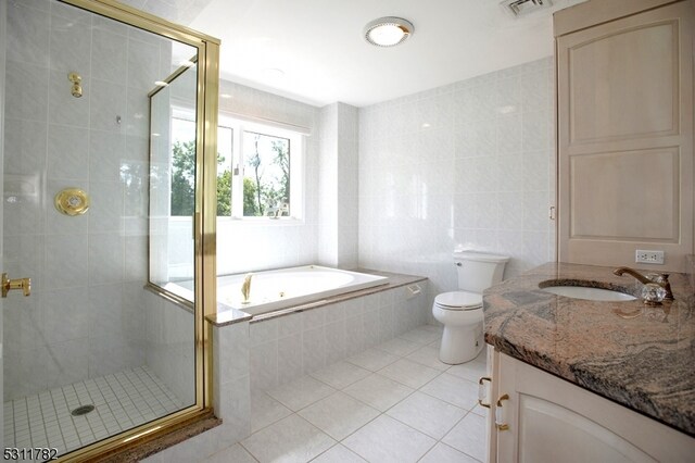 full bathroom with vanity, tile patterned flooring, toilet, tile walls, and independent shower and bath