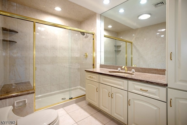 bathroom featuring tile patterned floors, vanity, a shower with shower door, and toilet