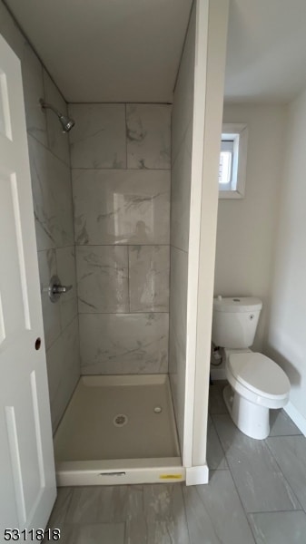 bathroom with toilet and a tile shower