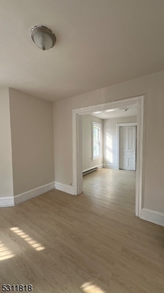 unfurnished room with light wood-type flooring and a baseboard heating unit