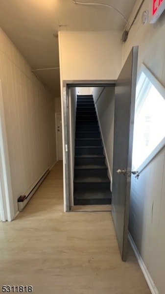 stairs featuring a baseboard heating unit and wood-type flooring