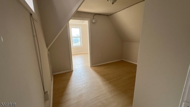 bonus room with light wood-type flooring and vaulted ceiling