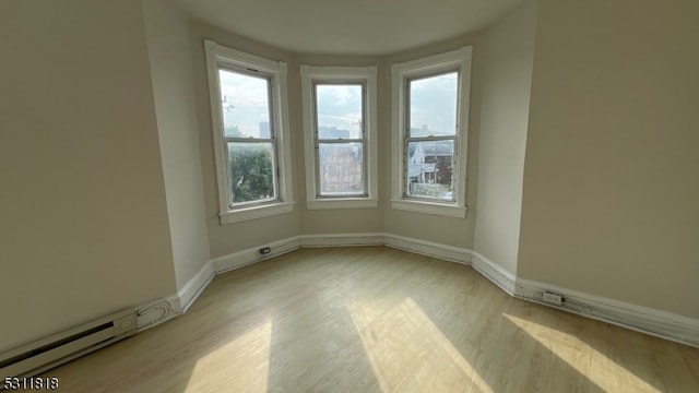 spare room with baseboard heating and light hardwood / wood-style floors