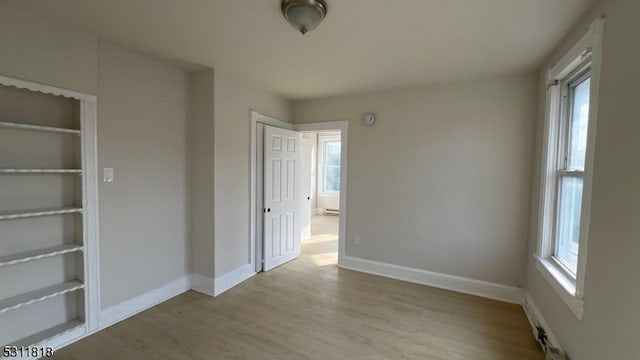 unfurnished bedroom featuring light wood-type flooring, multiple windows, and a closet