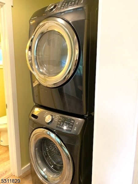 washroom featuring stacked washer and dryer and hardwood / wood-style flooring