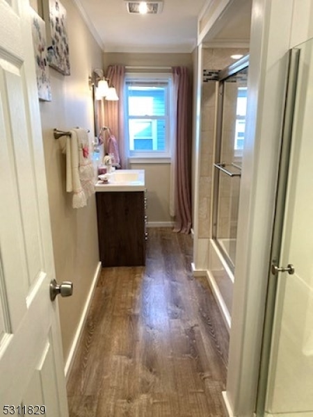 bathroom featuring shower / bathtub combination with curtain, ornamental molding, hardwood / wood-style flooring, and vanity