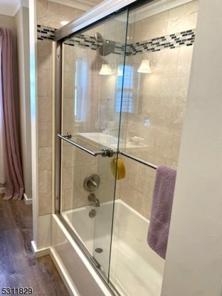 bathroom featuring crown molding, hardwood / wood-style flooring, and combined bath / shower with glass door