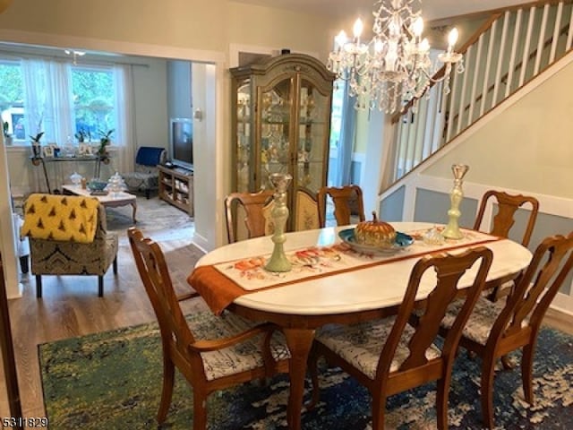 dining space featuring wood-type flooring and a notable chandelier