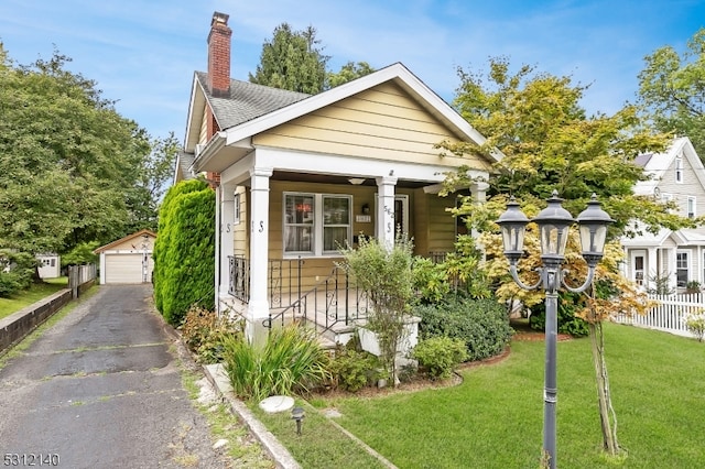 view of front of home featuring an outbuilding, a garage, a porch, and a front yard