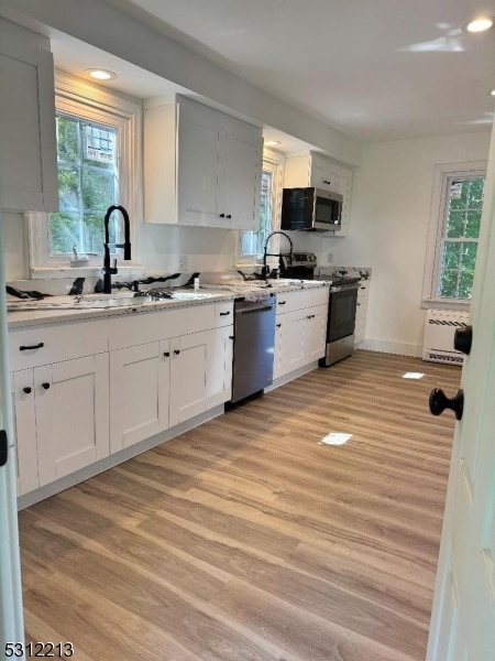 kitchen with white cabinetry, stainless steel appliances, sink, and light wood-type flooring