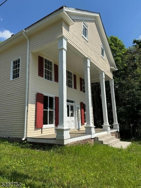 back of property featuring a lawn and a porch