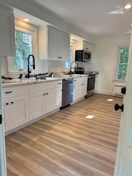 kitchen featuring light hardwood / wood-style floors, stainless steel appliances, sink, and white cabinets