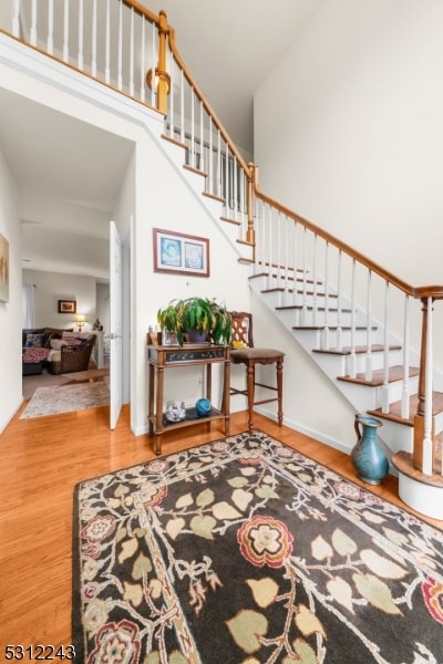 stairs with a towering ceiling and hardwood / wood-style floors