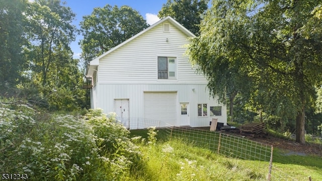 rear view of house featuring a garage and a yard