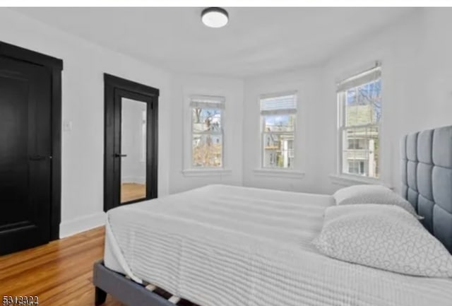 bedroom with multiple windows and hardwood / wood-style flooring