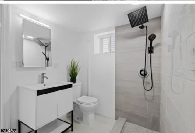 bathroom with tiled shower, toilet, and vanity