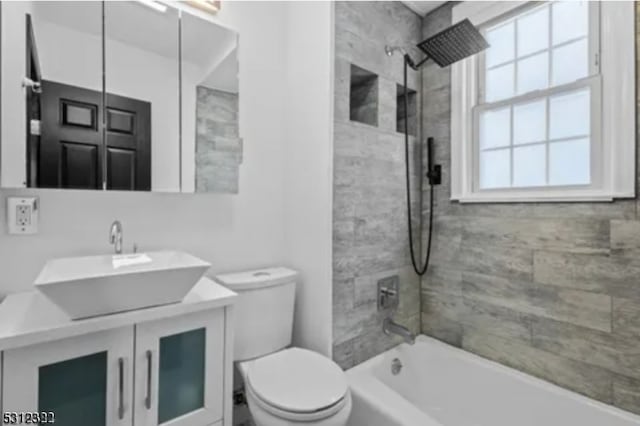 full bathroom with a wealth of natural light, vanity, toilet, and tiled shower / bath combo