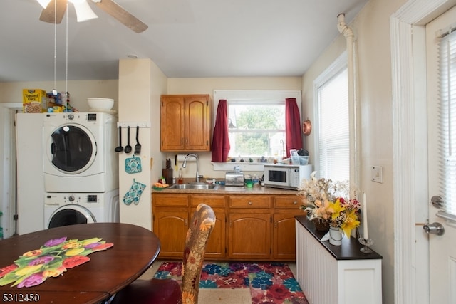 kitchen with ceiling fan, stacked washer / drying machine, and sink