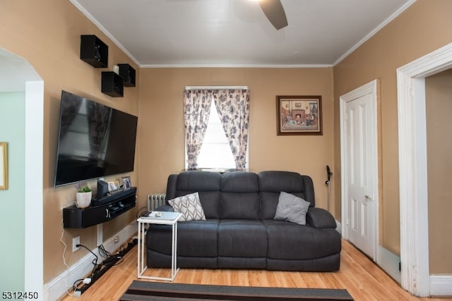 living room featuring radiator heating unit, hardwood / wood-style flooring, ceiling fan, and crown molding