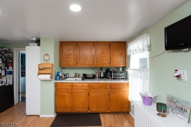 kitchen with black refrigerator, light hardwood / wood-style flooring, and sink