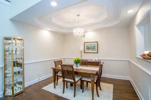 dining space featuring crown molding, a tray ceiling, dark hardwood / wood-style floors, and a chandelier