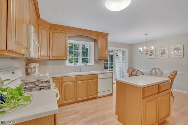 kitchen with a center island, decorative light fixtures, white appliances, light hardwood / wood-style floors, and a notable chandelier