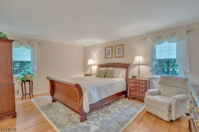 bedroom featuring crown molding, multiple windows, and light hardwood / wood-style floors