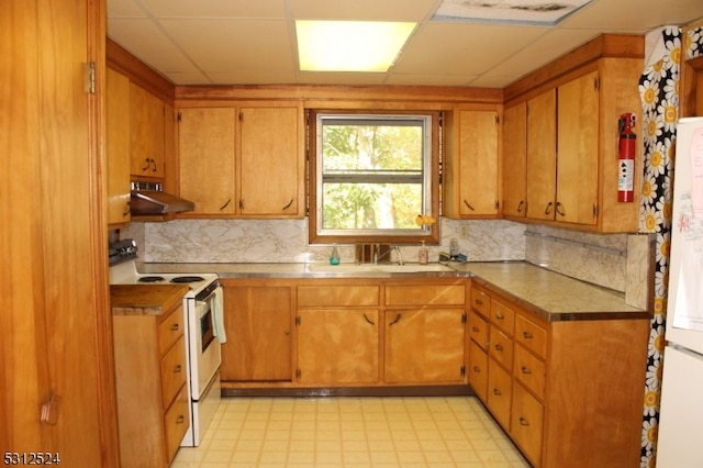 kitchen with a paneled ceiling, white appliances, decorative backsplash, and sink