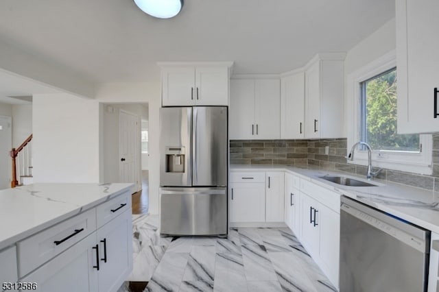 kitchen featuring light stone countertops, tasteful backsplash, sink, white cabinetry, and appliances with stainless steel finishes