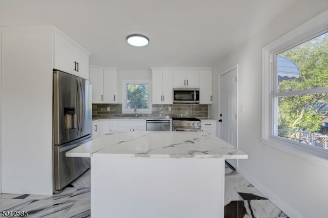 kitchen with appliances with stainless steel finishes, white cabinetry, decorative backsplash, and a center island