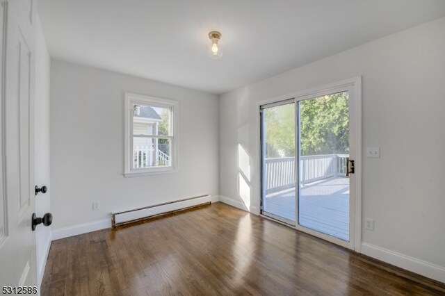 unfurnished room with baseboard heating, dark hardwood / wood-style flooring, and a wealth of natural light