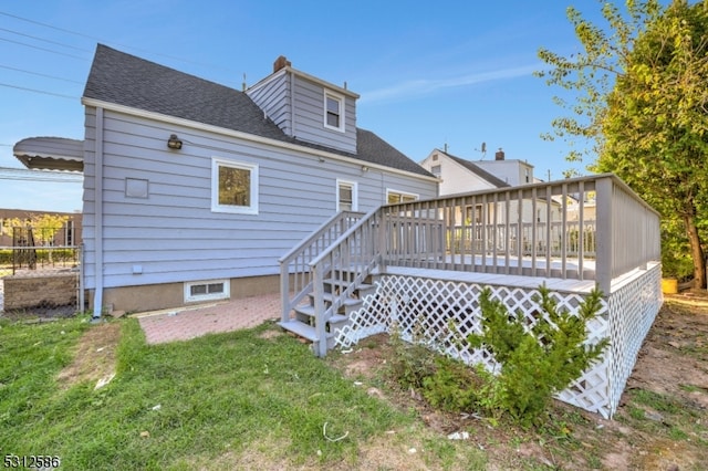 back of house with a deck and a lawn