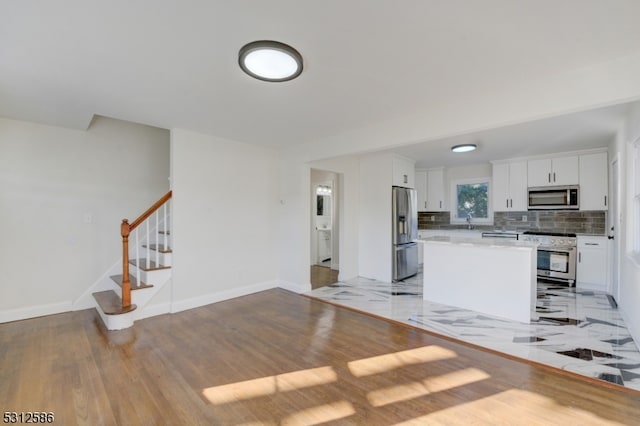 kitchen with tasteful backsplash, a kitchen island, sink, appliances with stainless steel finishes, and white cabinetry