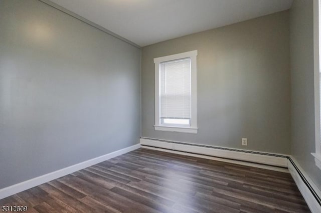 spare room with dark wood-type flooring and a baseboard radiator