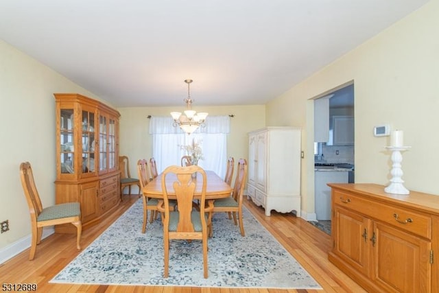 dining space with an inviting chandelier and light hardwood / wood-style flooring