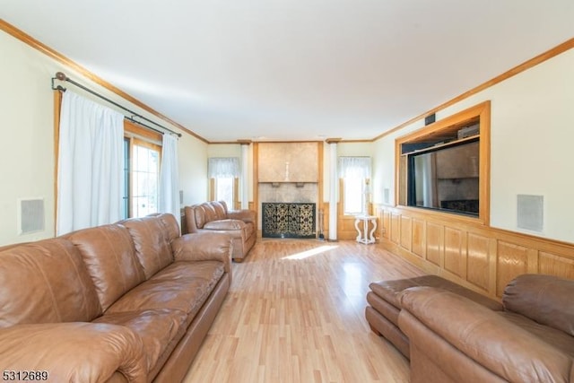 living room featuring light hardwood / wood-style floors, crown molding, and a large fireplace