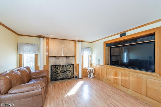 unfurnished living room with light wood-type flooring, a large fireplace, and ornamental molding