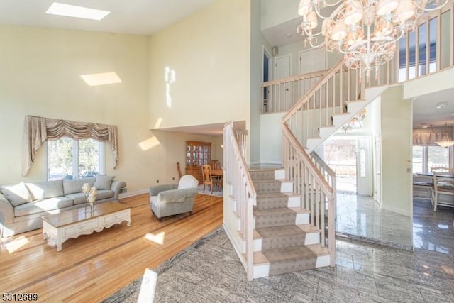 living room with a skylight, a towering ceiling, an inviting chandelier, and plenty of natural light