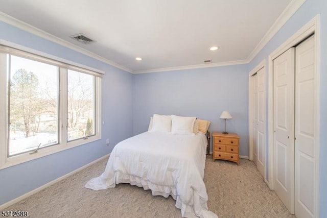 carpeted bedroom featuring multiple closets and ornamental molding