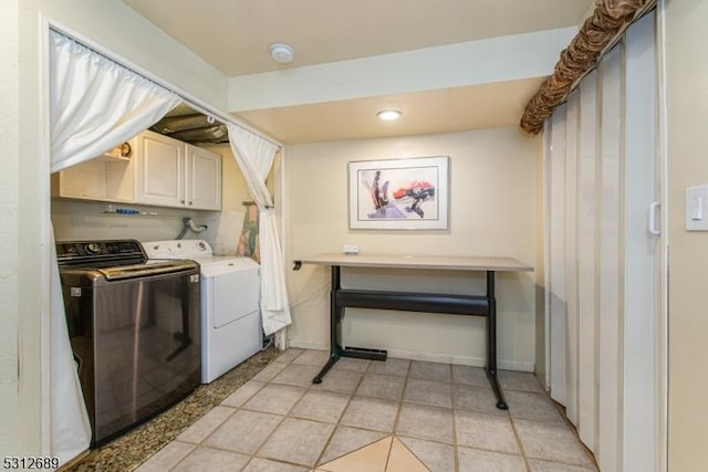 laundry room featuring washing machine and dryer, cabinets, and light tile patterned floors