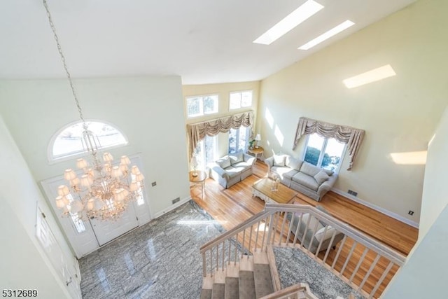 living room featuring an inviting chandelier, high vaulted ceiling, plenty of natural light, and hardwood / wood-style floors