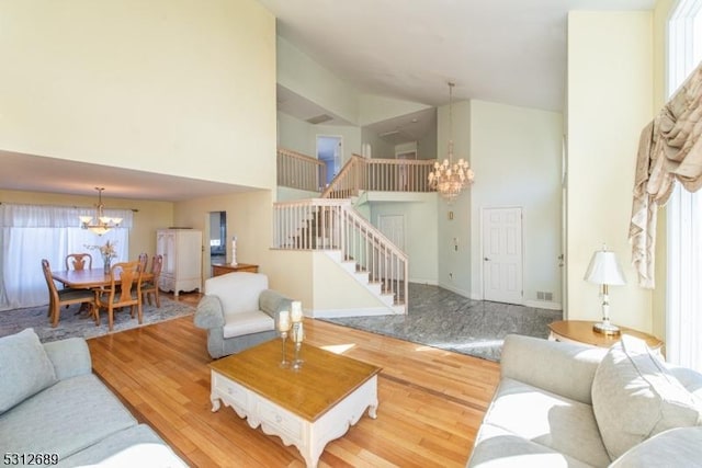 living room with high vaulted ceiling, a chandelier, and hardwood / wood-style flooring