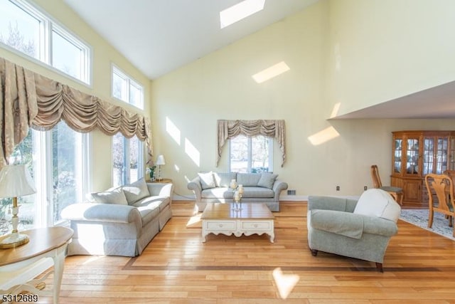 living room featuring light wood-type flooring and vaulted ceiling with skylight