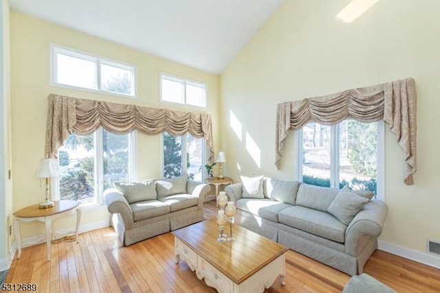 living room featuring light wood-type flooring and high vaulted ceiling