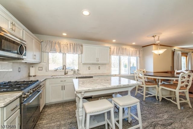 kitchen with appliances with stainless steel finishes, a kitchen island, sink, and white cabinetry