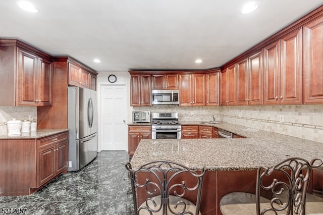 kitchen featuring appliances with stainless steel finishes, kitchen peninsula, tasteful backsplash, and a breakfast bar