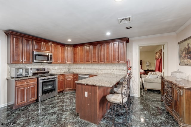 kitchen featuring light stone countertops, backsplash, appliances with stainless steel finishes, and a breakfast bar area