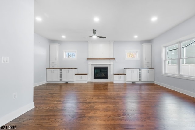 unfurnished living room with a large fireplace, dark hardwood / wood-style floors, and ceiling fan