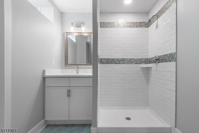 bathroom with a tile shower and vanity