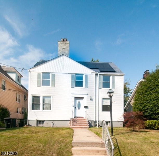 view of front facade with solar panels and a front lawn